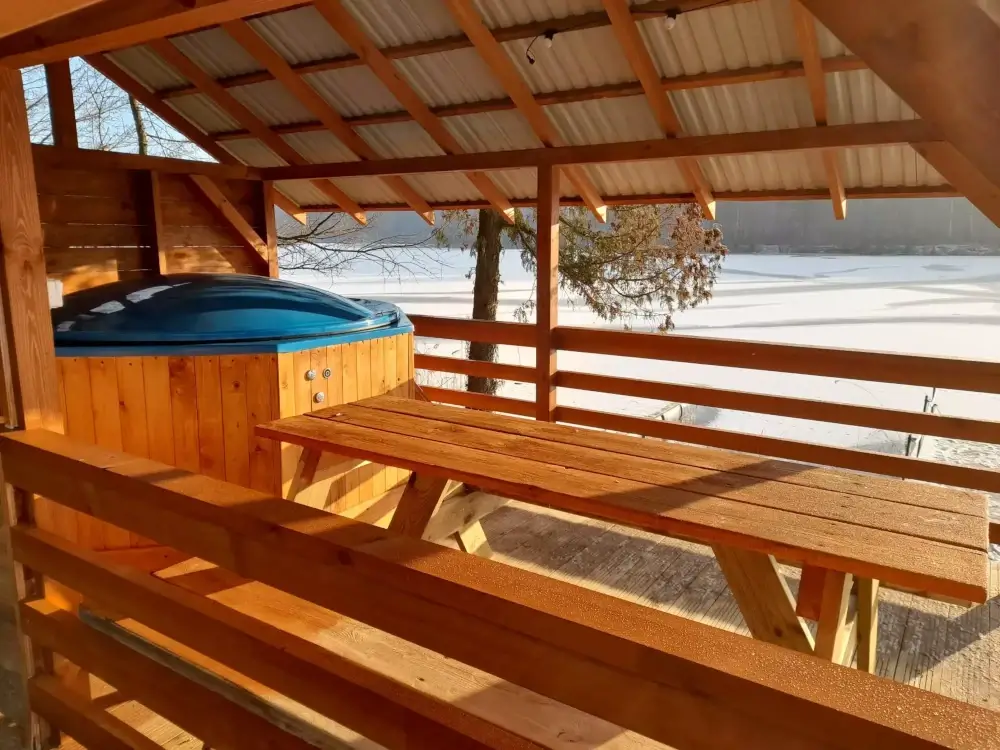 Duża drewniana bania pod zadaszeniem, ze stolikiem i bezpośrednim dostępem do jeziora