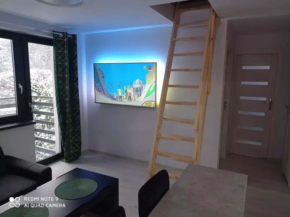 Jasny salon z wygodną kanapą, telewizorem i wygodnym miejscem do wypoczynku po dniu nad jeziorem