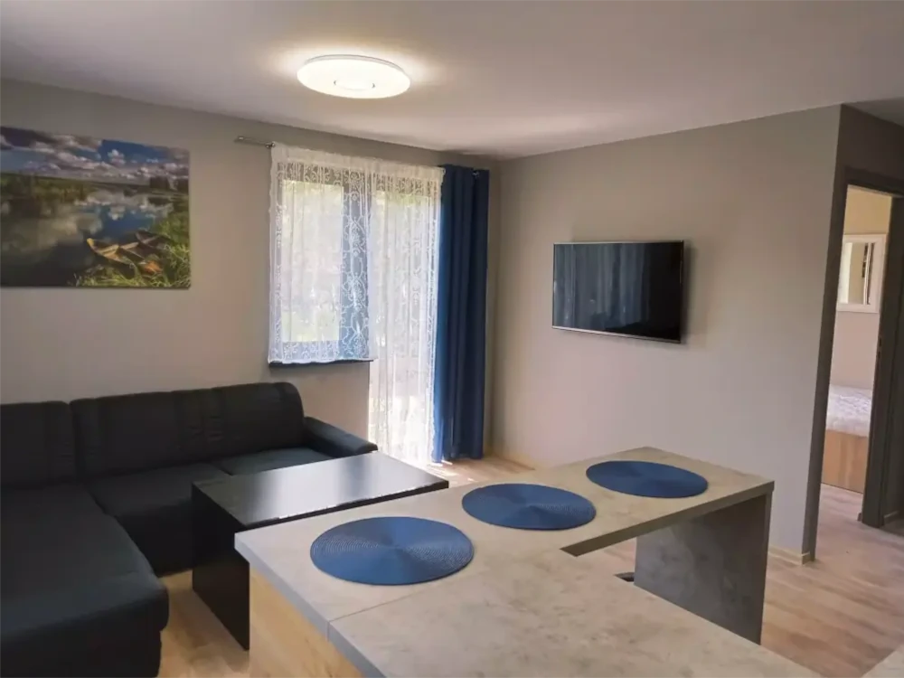 Przytulny salon z wygodną kanapą, stolikiem kawowym i widokiem na jezioro Studzieniczne