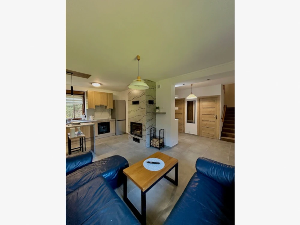 Nowoczesny, jasny salon z kominkiem i wygodną skórzaną kanapą