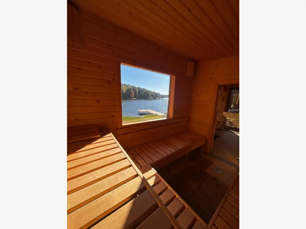 Wnętrze sauny z drewnianymi ławkami i widokiem na jezioro