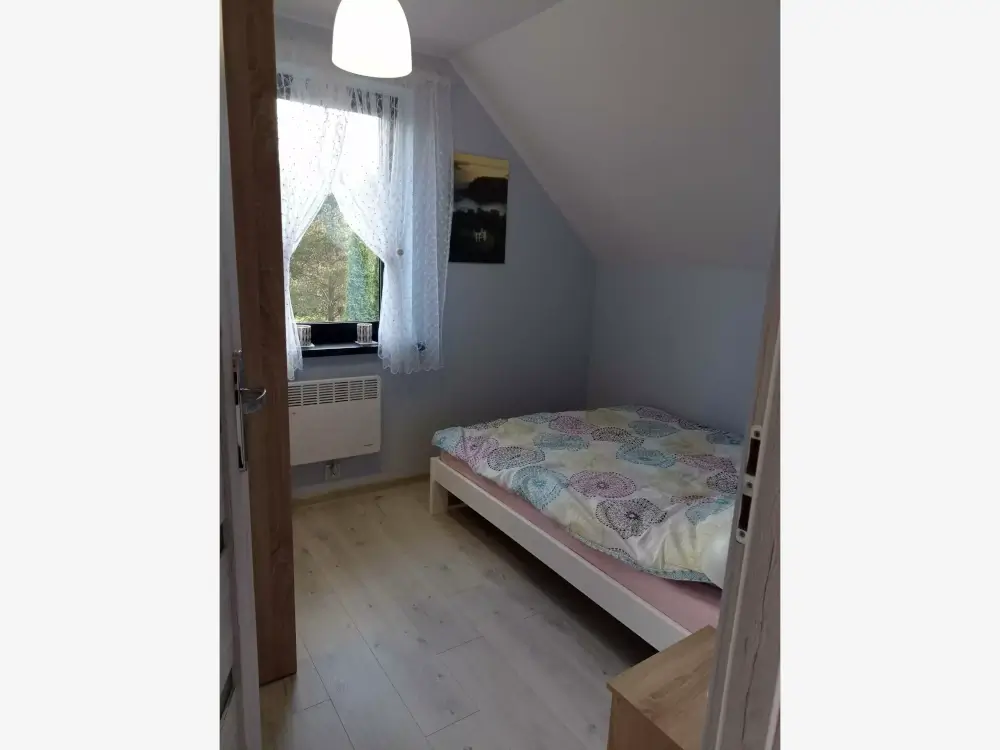 Jasna sypialnia z podwójnym łóżkiem i dużą szafą